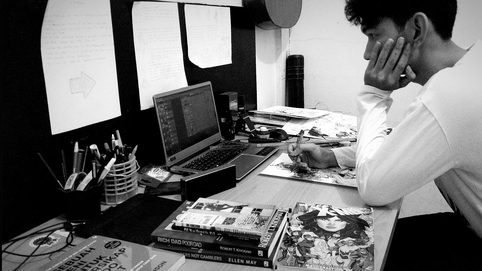 Black-and-white studio photograph of Aditya Wardana drawing